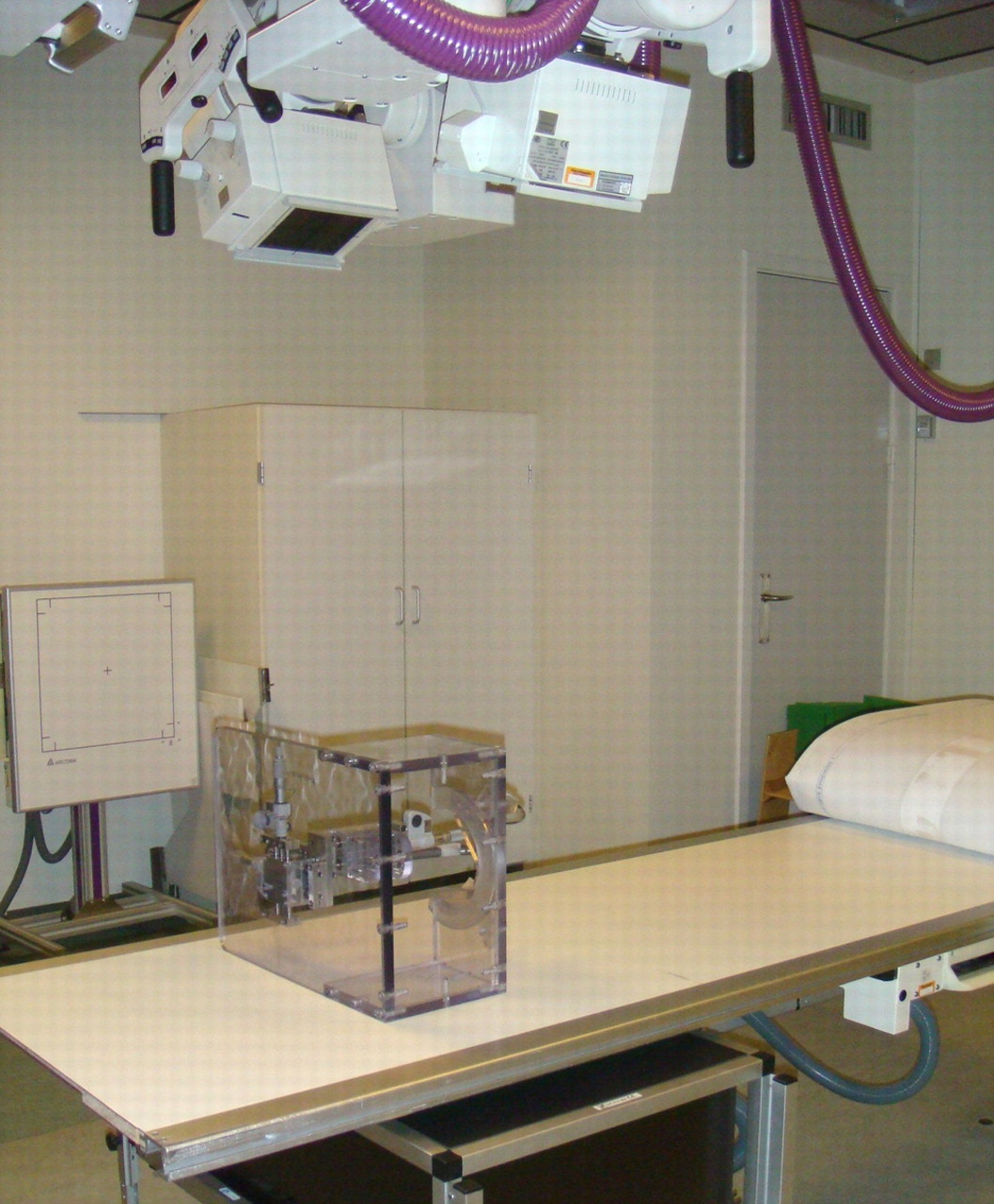 Fig. 2 
            Photograph showing the stereo radiological
setup with two synchronised ceiling-fixed roentgen tubes, the hip
phantom on its side, and a uniplanar carbon calibration box with
digital films.
          